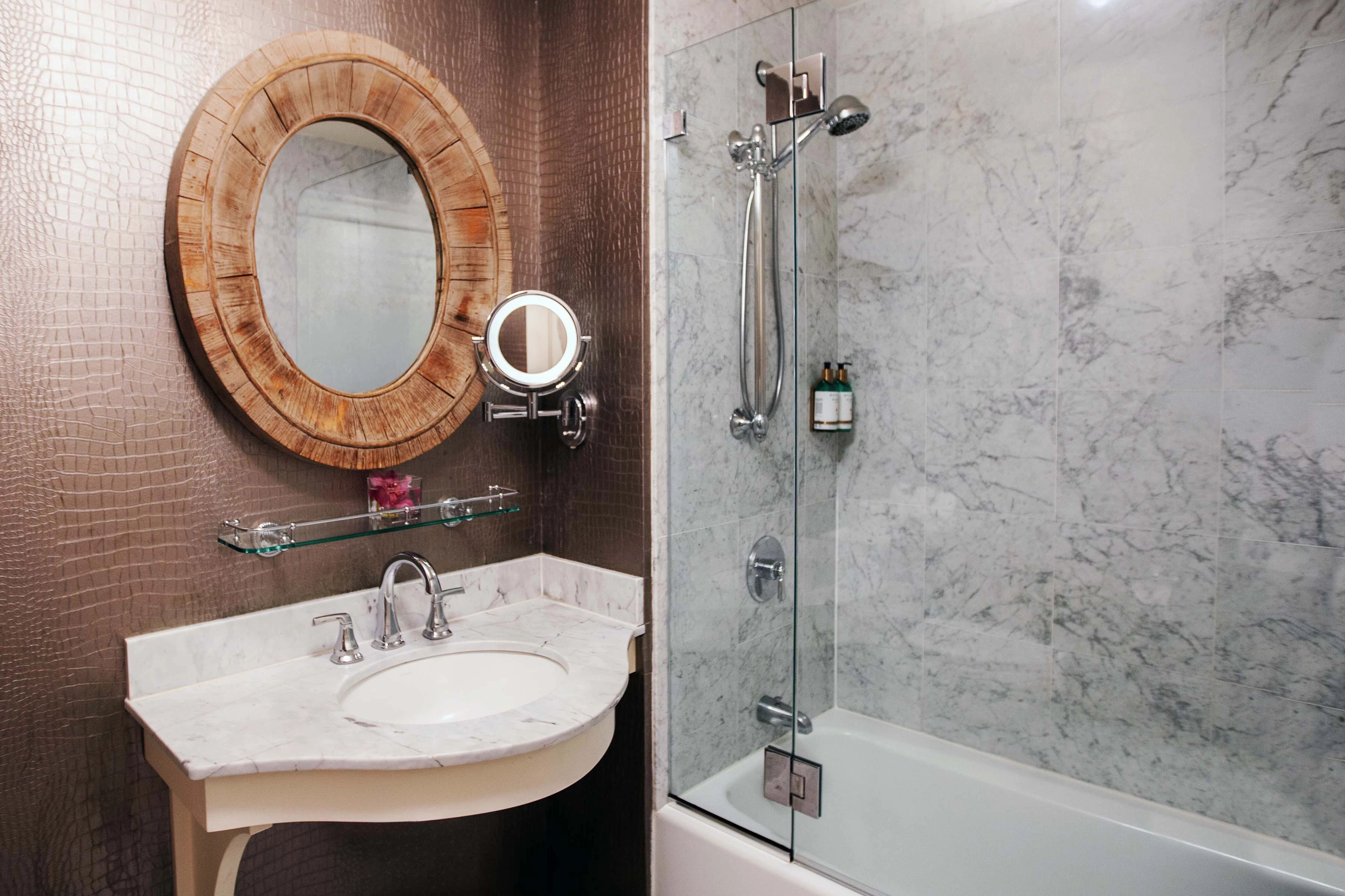 A modern bathroom with a marble sink, glass-enclosed shower, and bathtub.