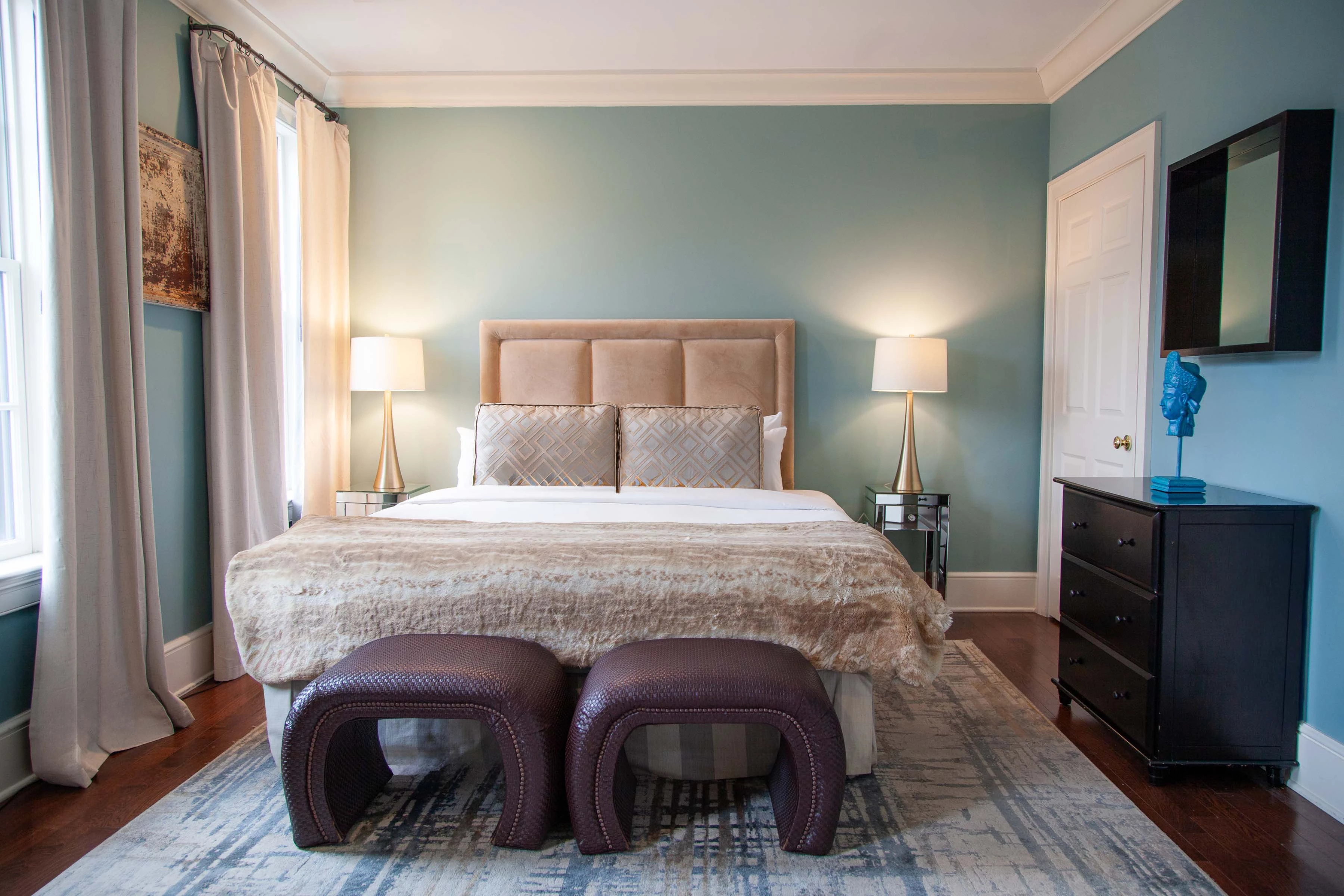 A neatly arranged bedroom with a large bed, two nightstands, a TV, and a dresser.