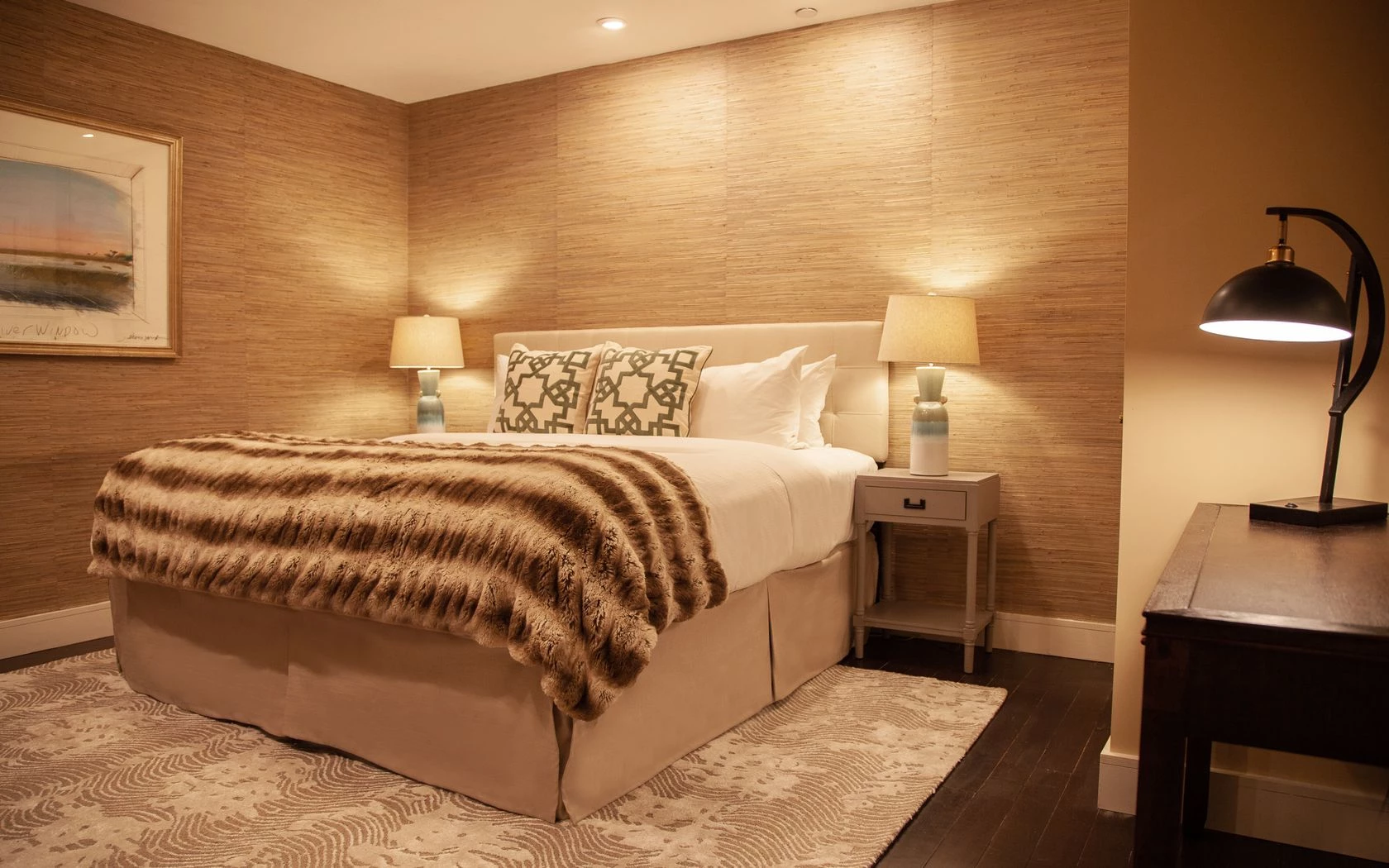A hotel room with a bed, nightstand, and lamp