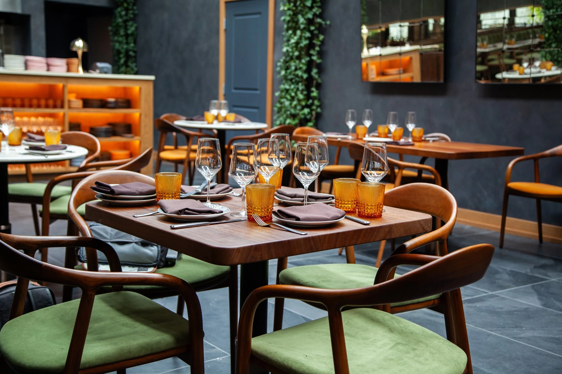 a table with glasses and plates in a room with green chairs