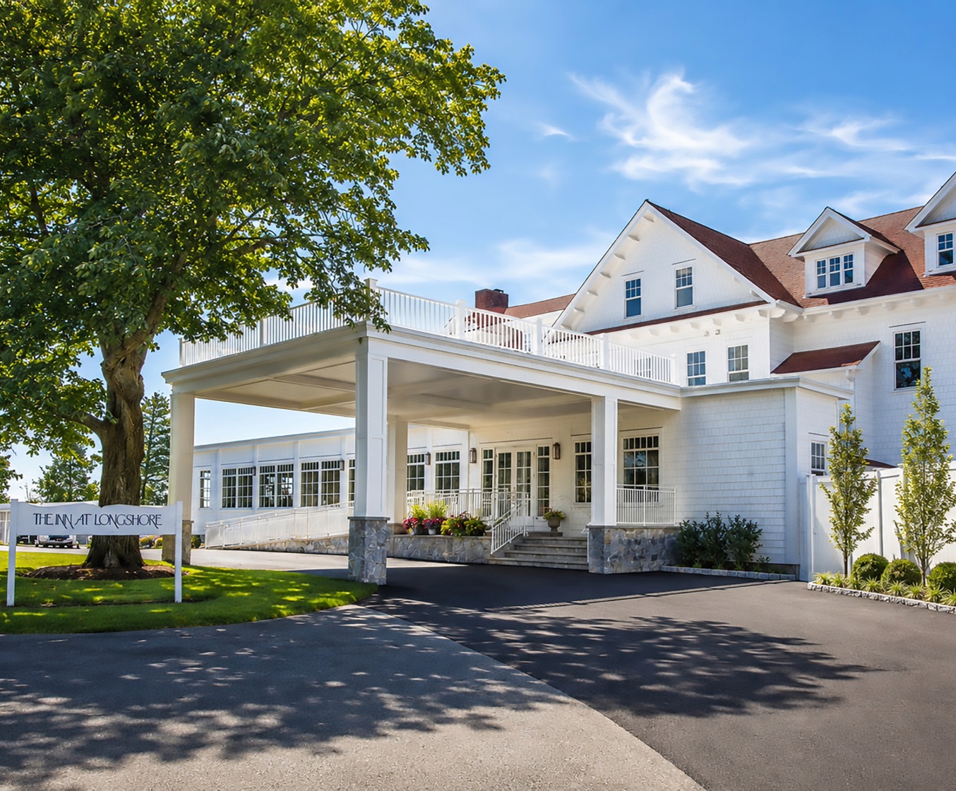 a large white building with a white porch and a tree