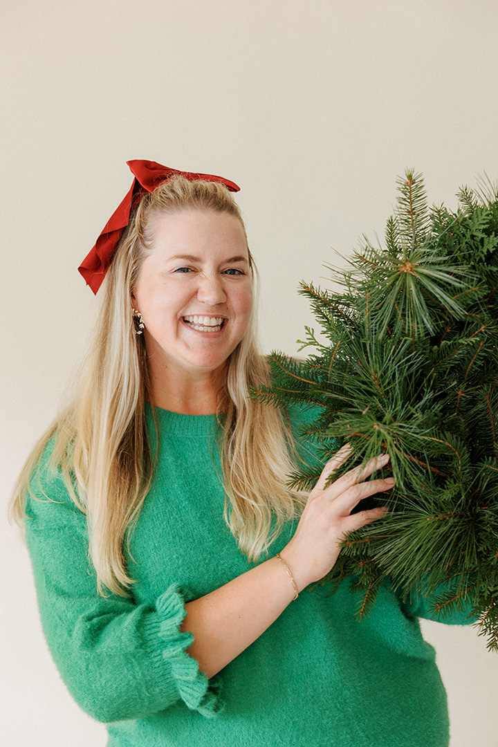 a woman smiling with a christmas tree