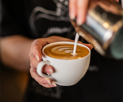 a person pouring milk into a cup of coffee