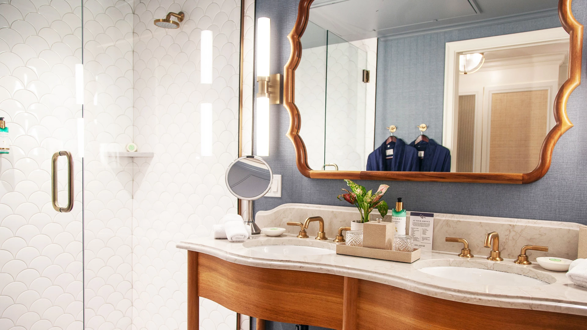 A bathroom with a double vanity, marble countertop, and gold fixtures.