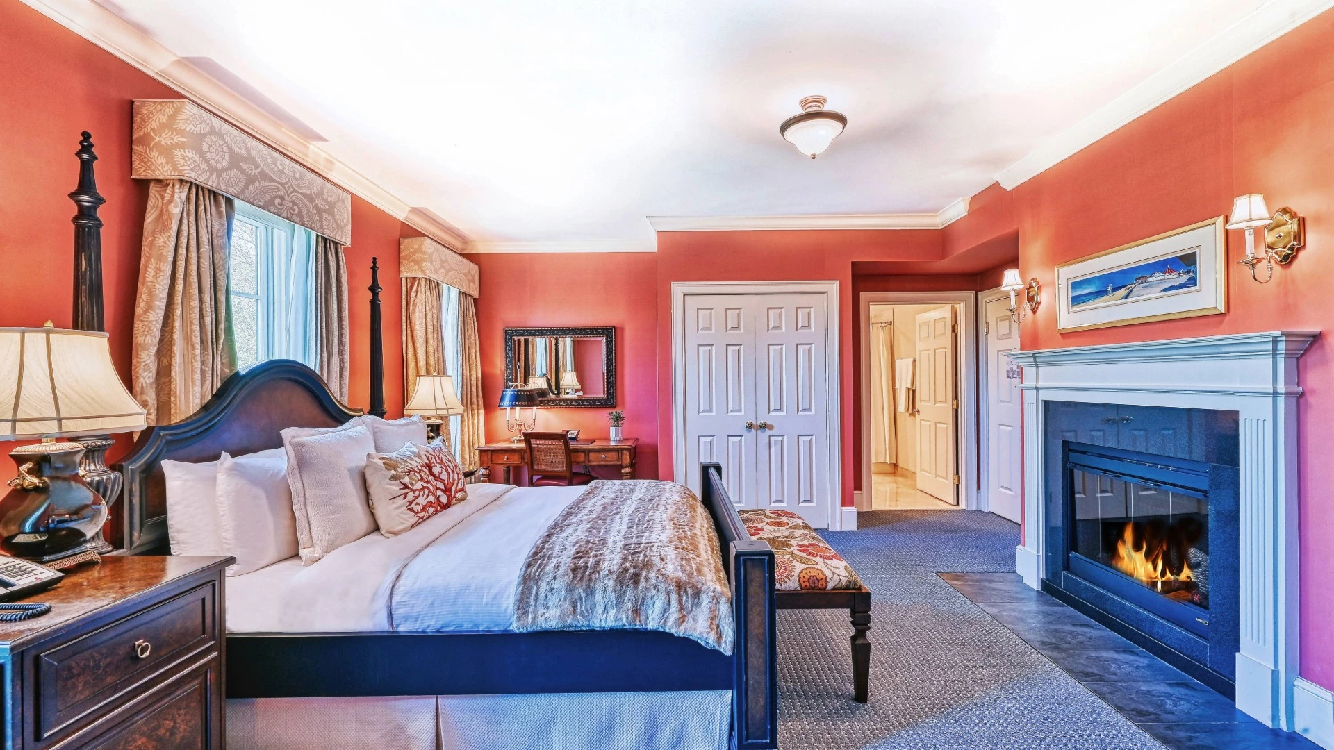 A wide view of a hotel room with a bed, fireplace, and doorway.