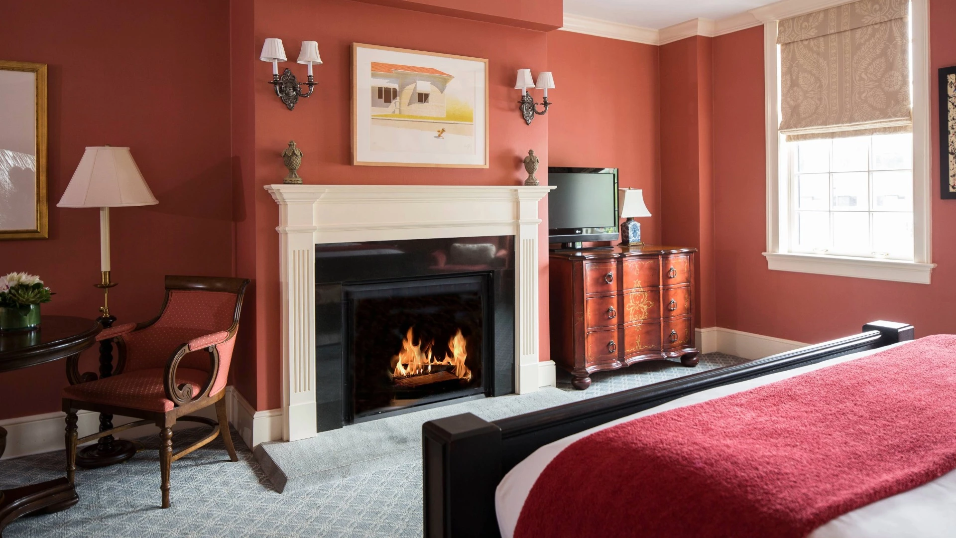 A cozy room with a fireplace, bed, chair, and TV.