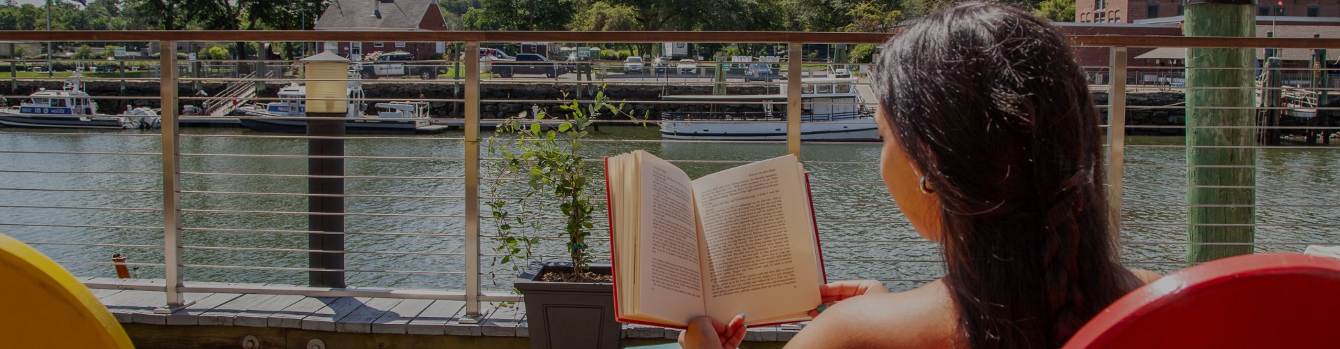 a person reading a book on a balcony overlooking a river