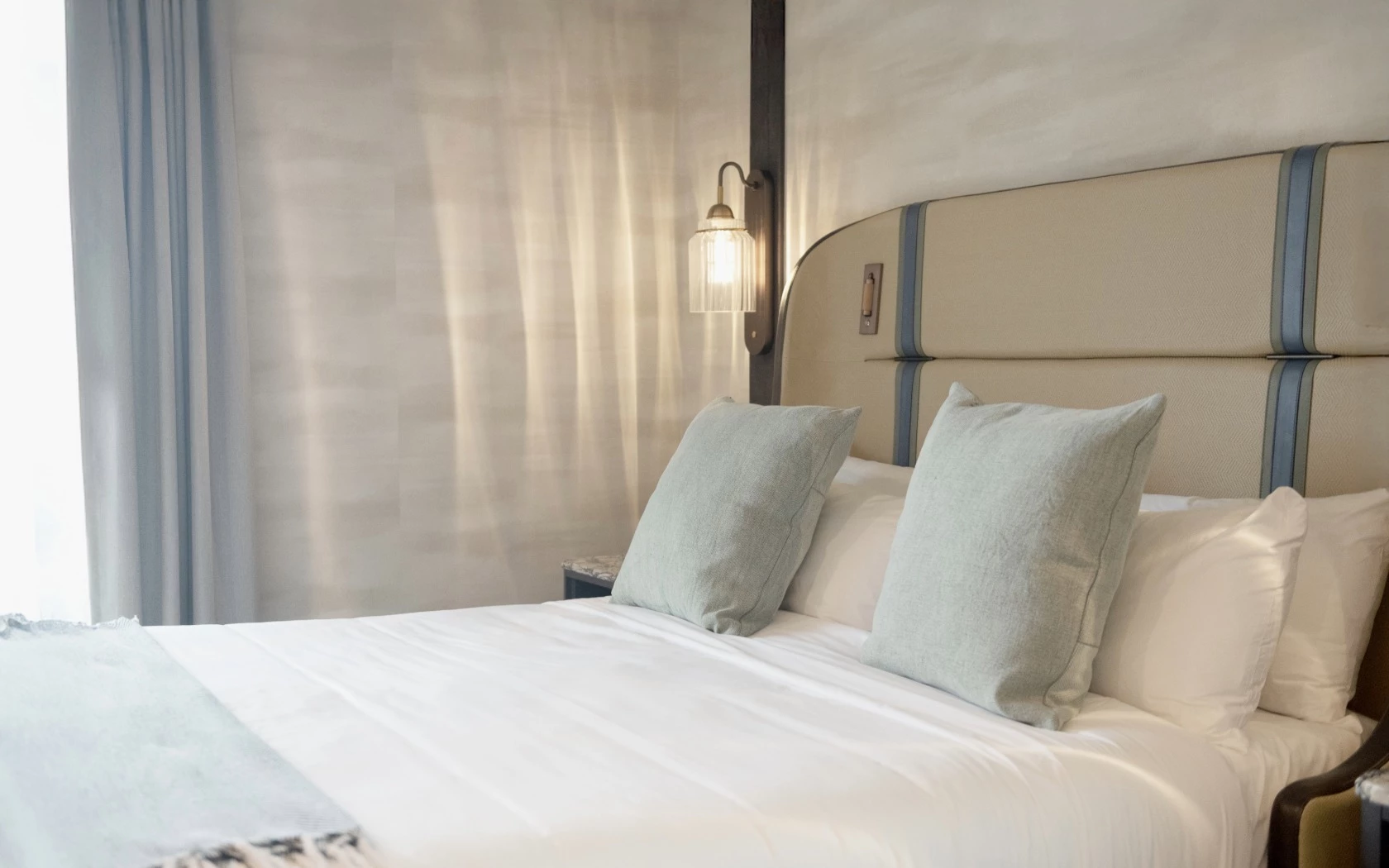 a neatly made bed with white sheets and pillows