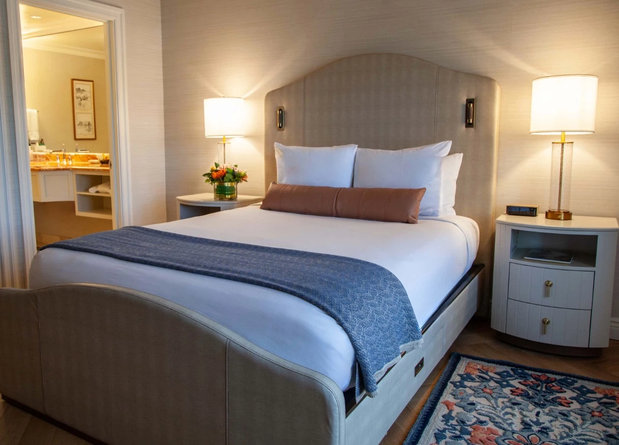 A hotel room with a bed, nightstands, and a doorway to the bathroom