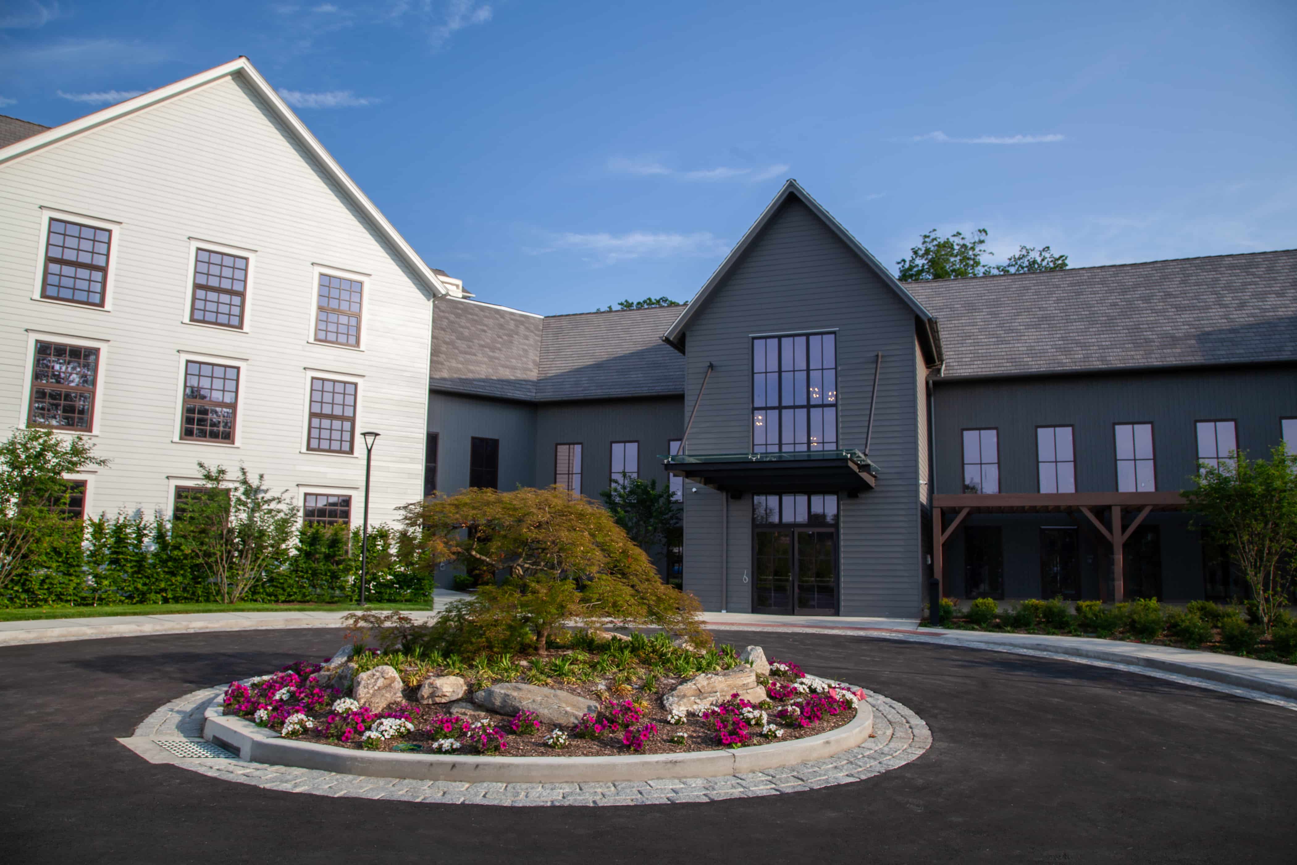 a building with a circular driveway and a tree in front