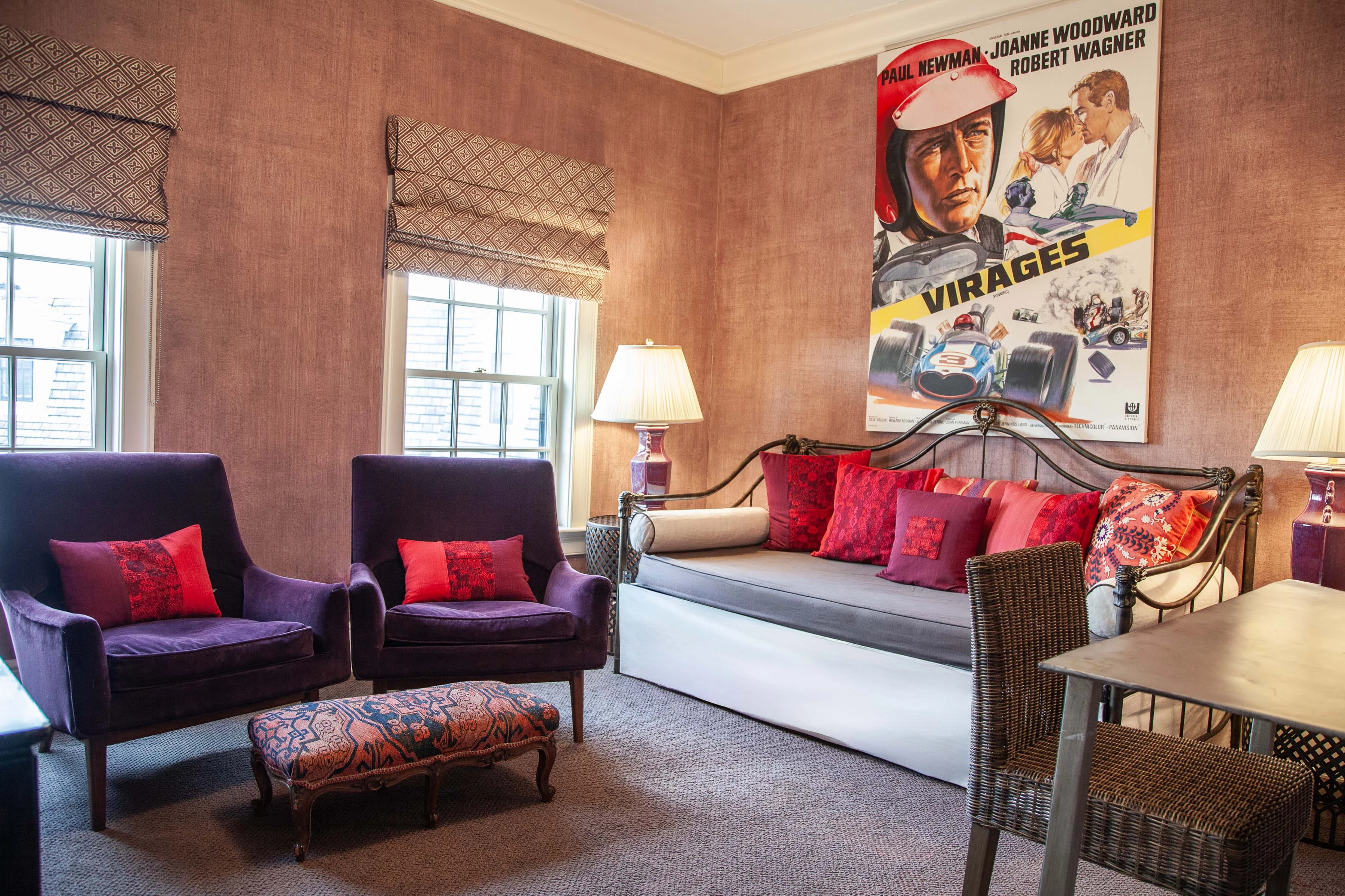 A wide shot of a room with a daybed, two chairs, and a table.