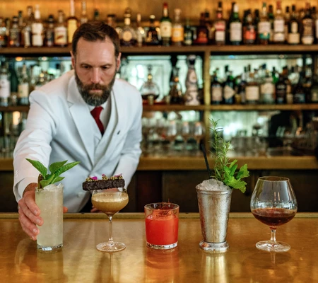 a man in a white suit holding a drink in a glass