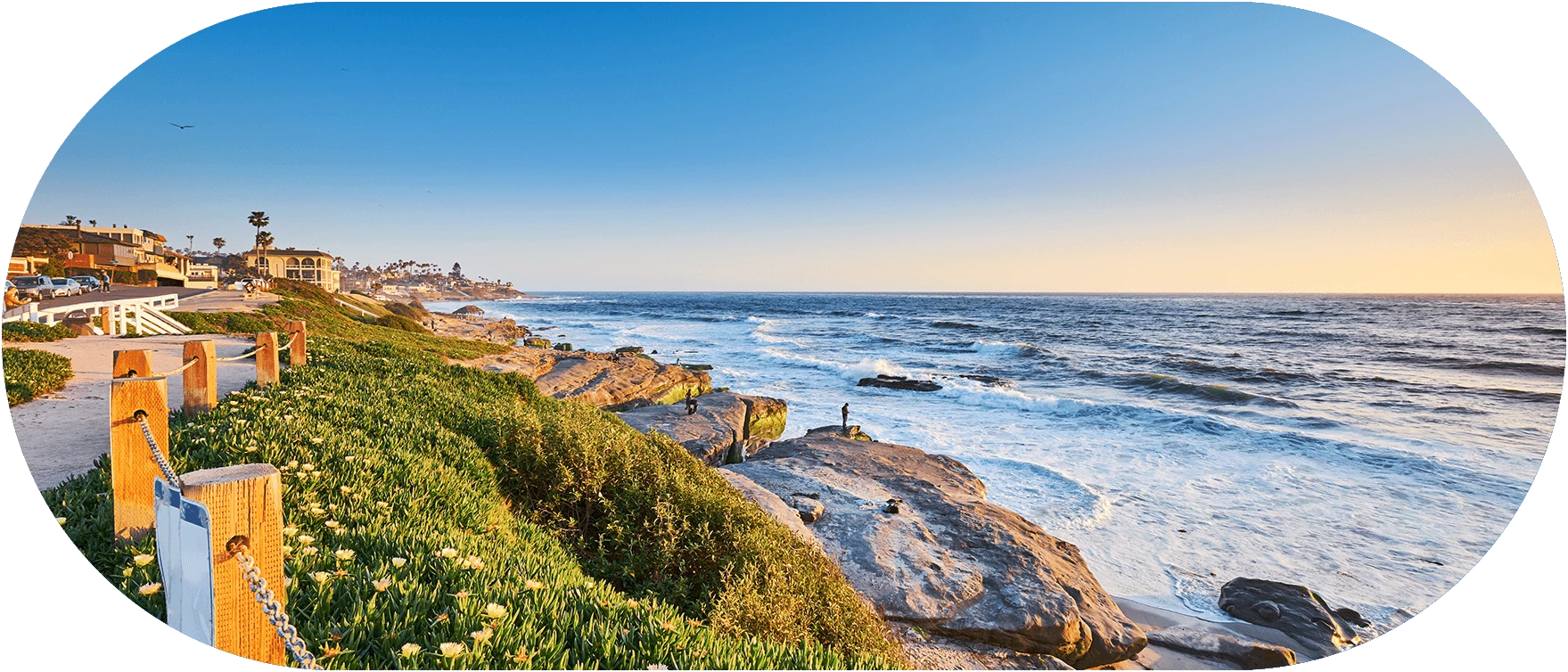 a rocky beach with a body of water and a blue sky