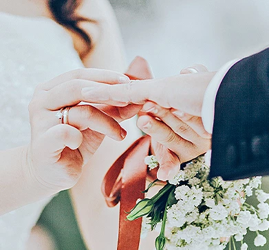 close up view of the hands of bride and groom putting their marriage ring on