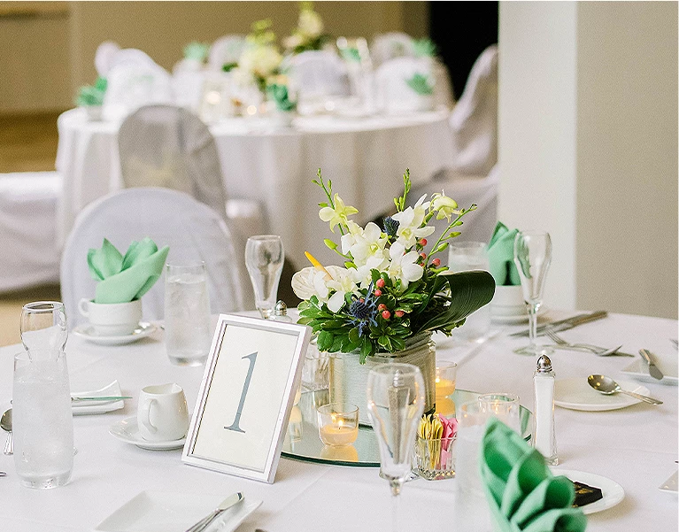 table setup for an event with a boutique of roses in the center of the table