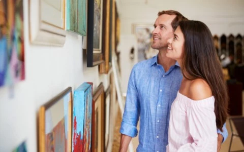couple looking at paintings in art gallery