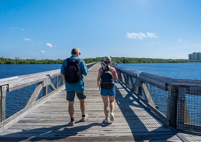 a man and woman walking on a wooden bridge over water