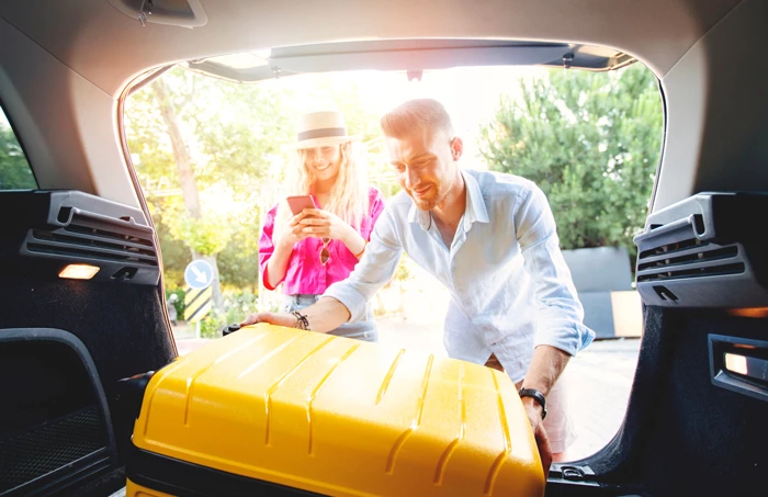 a man and woman loading luggage into a car