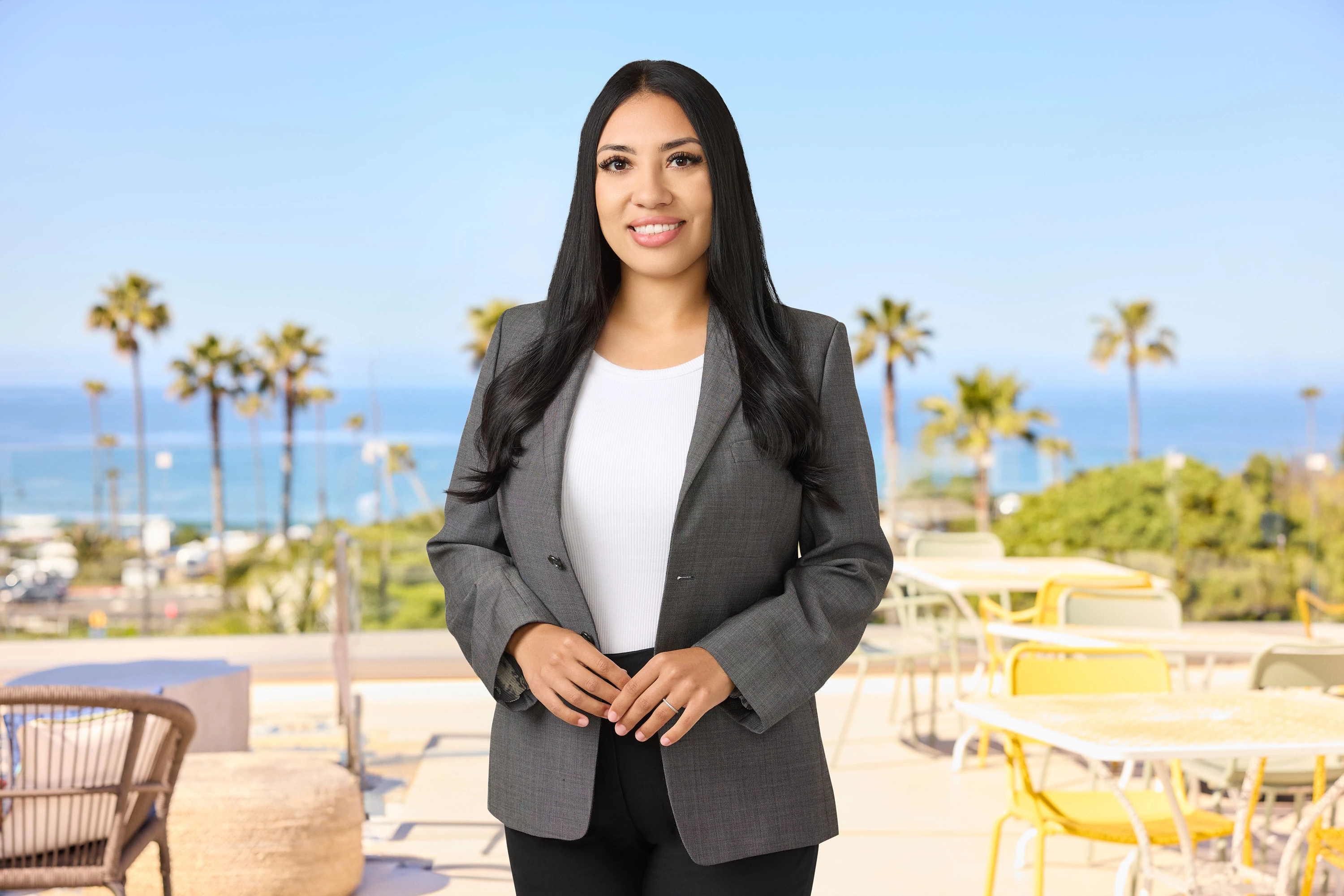 a woman standing outside with palm trees and a blue sky
