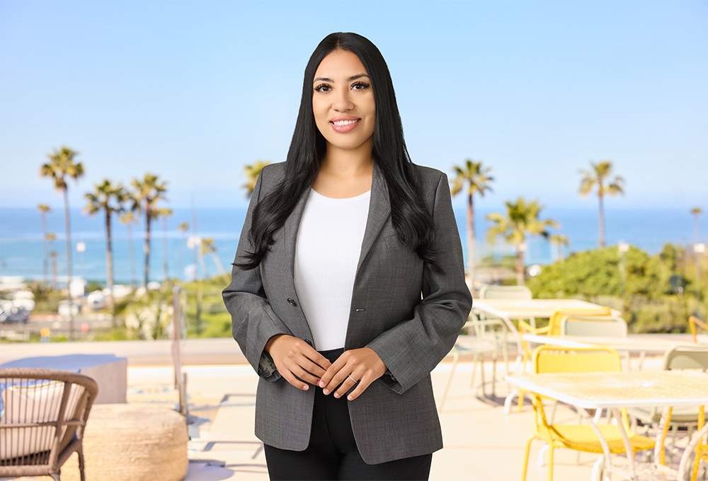 a woman standing outside with a table and chairs and palm trees