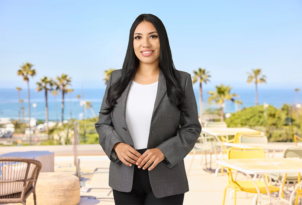a woman standing outside with a table and chairs and palm trees
