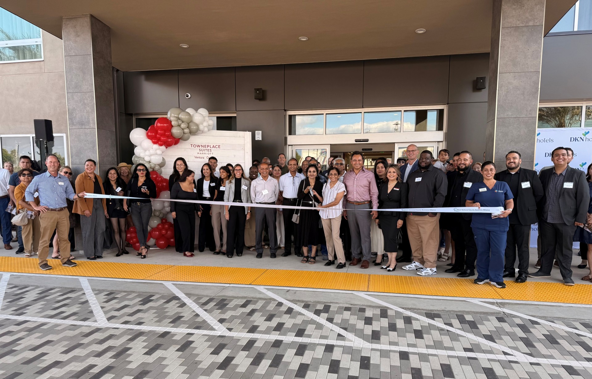 a group of people standing in front of a ribbon cutting