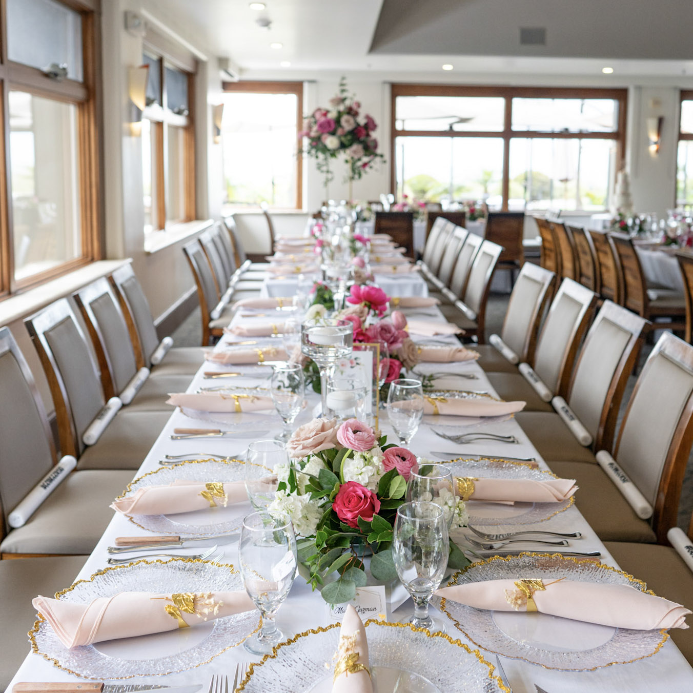 Rustic-coastal wedding reception in the Lido Restaurant & Lounge Dining Room at Dolphin Bay Resort & Spa in Pismo Beach — long wooden table with pink flowers, soft coastal tones, and ocean-view ambiance for intimate celebrations.