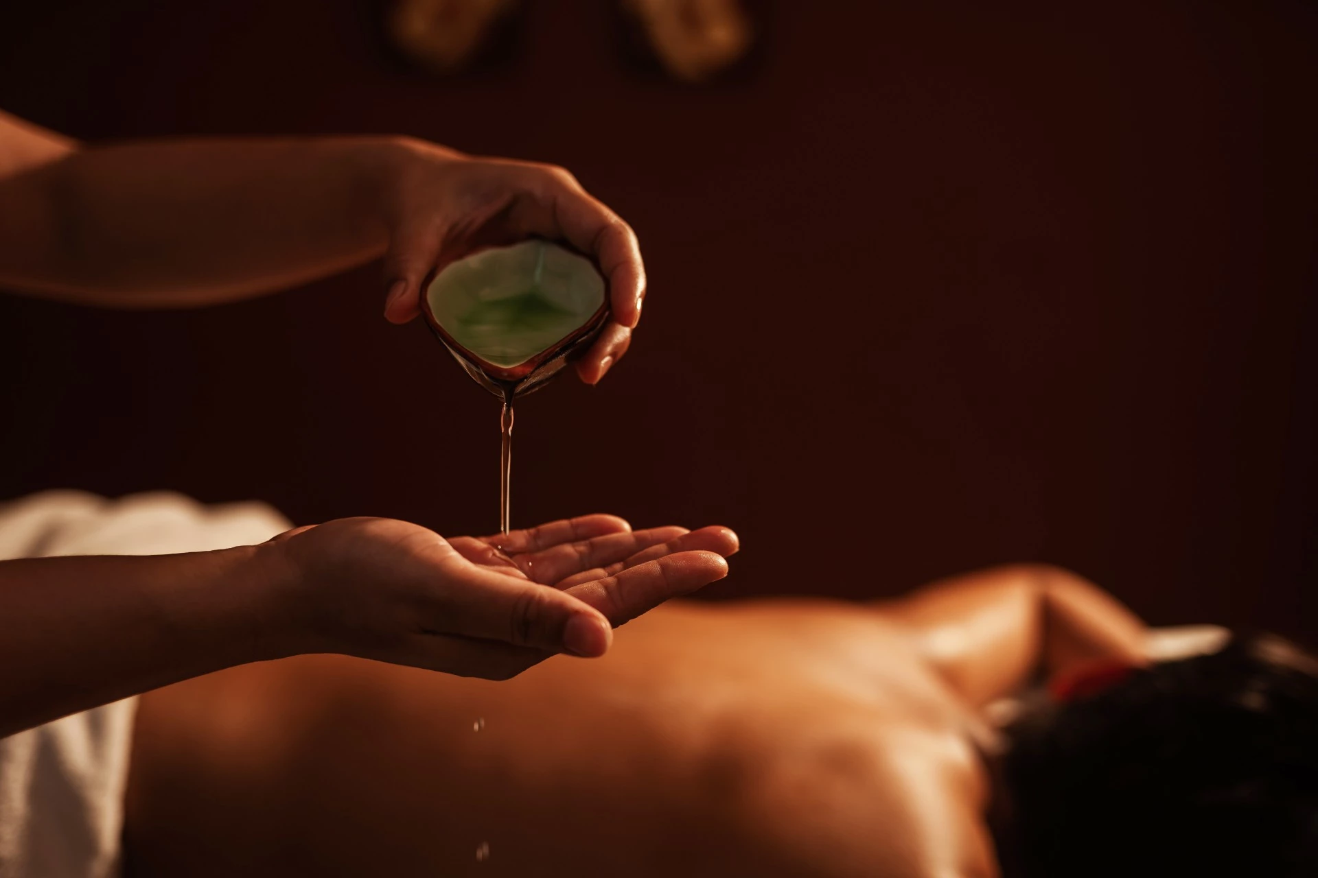 a person pouring oil onto a person's hand