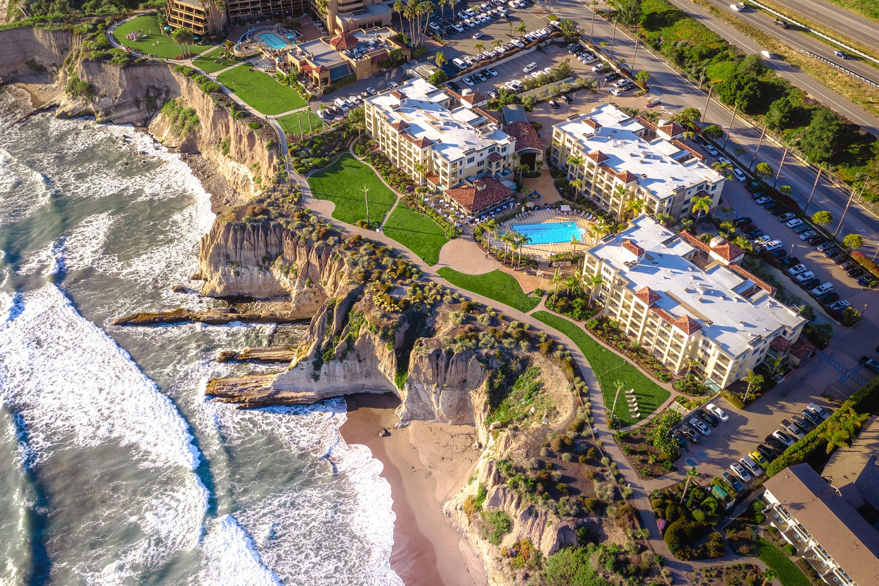 a aerial view of a beach with buildings and a pool