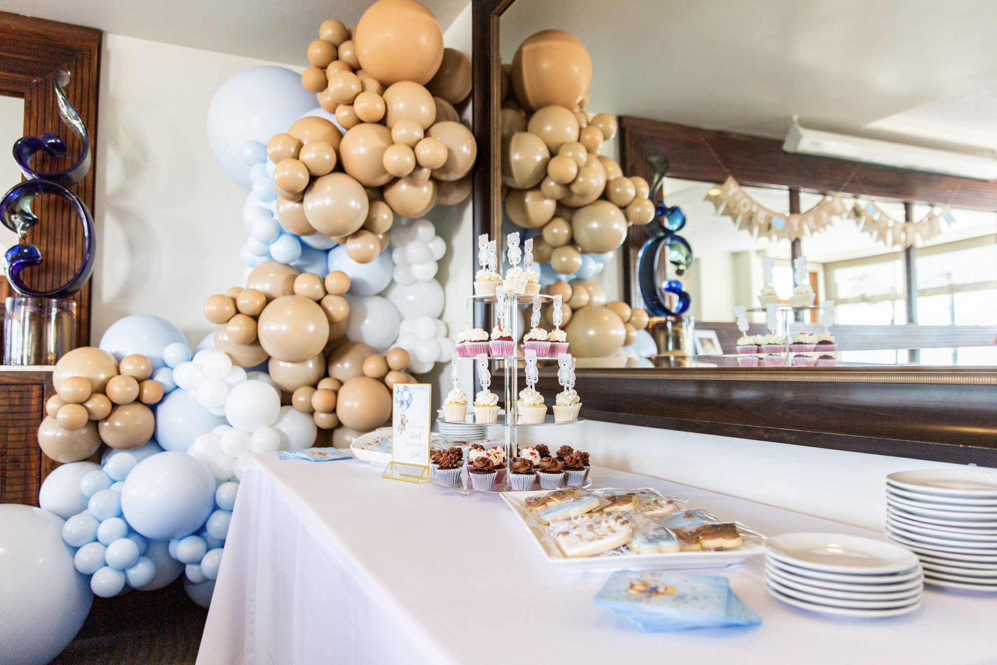Custom baby shower dessert table by the in-house pastry chef at Lido Restaurant & Lounge featuring sweet treats, balloons, and white linens at Dolphin Bay Resort & Spa.