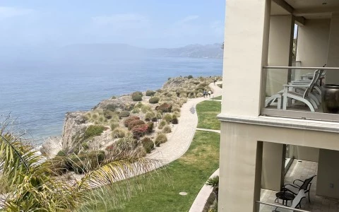 a building with a grassy hill and a body of water in the background