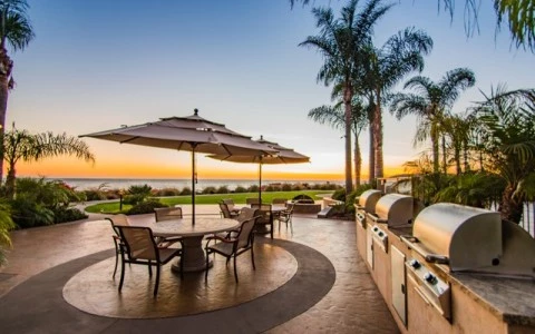 a patio with a table and chairs and umbrellas by a beach