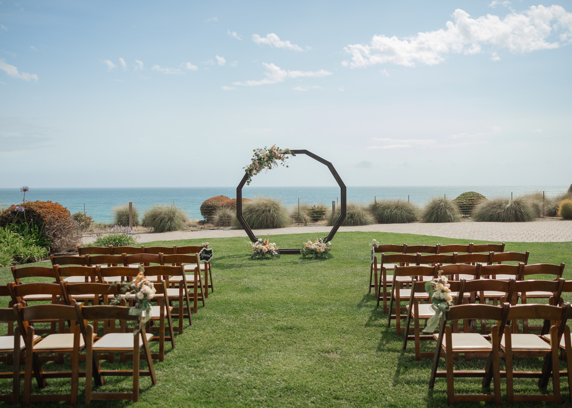 Cliffside lawn wedding ceremony at Dolphin Bay Resort & Spa in Pismo Beach — oceanfront vows surrounded by lush greenery and sweeping coastal views.
