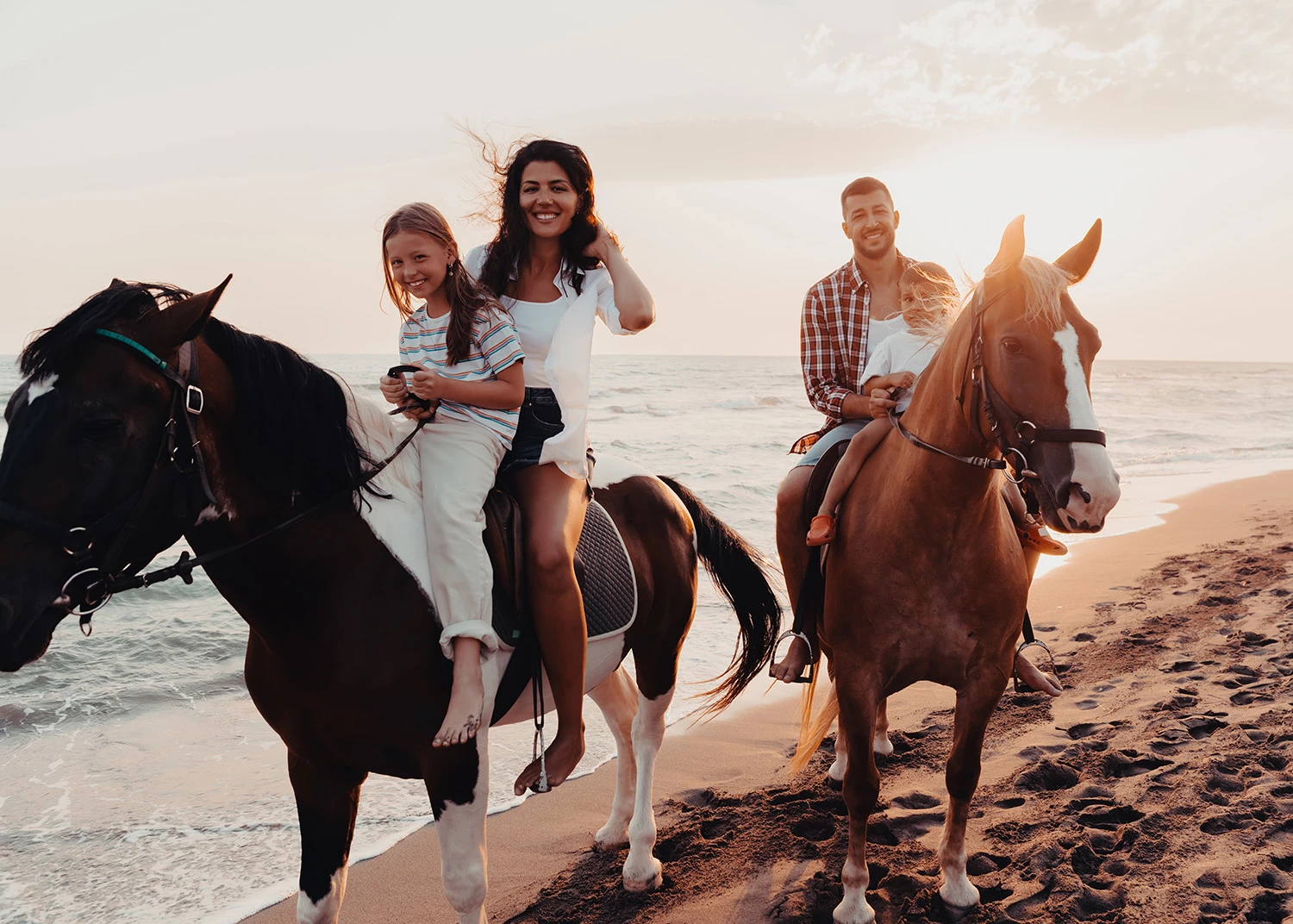 a man and woman riding horses on a beach