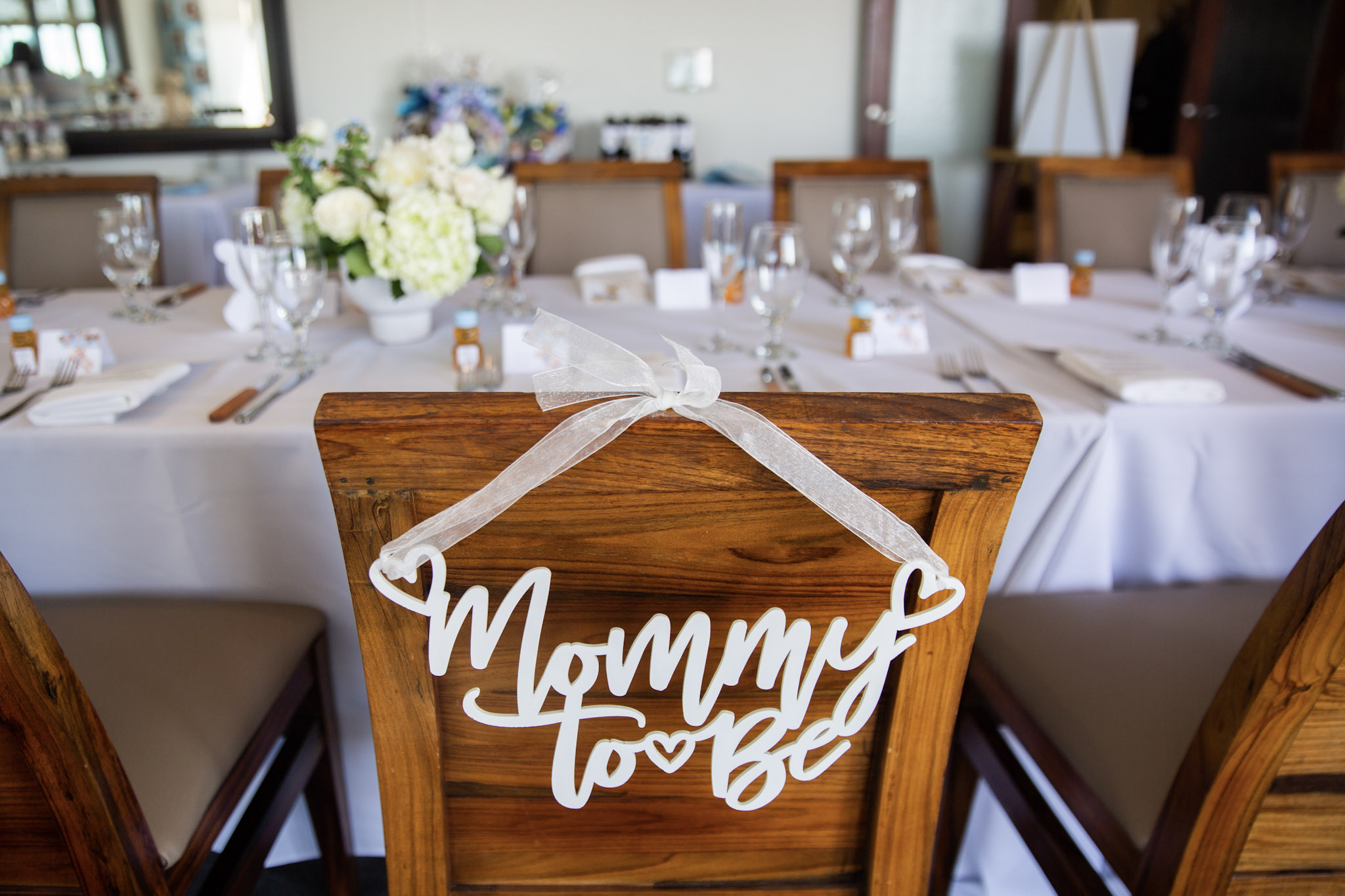 Baby shower table display with ‘Mommy to Be’ sign, flowers, and personalized party favors at Dolphin Bay Resort & Spa in Pismo Beach.