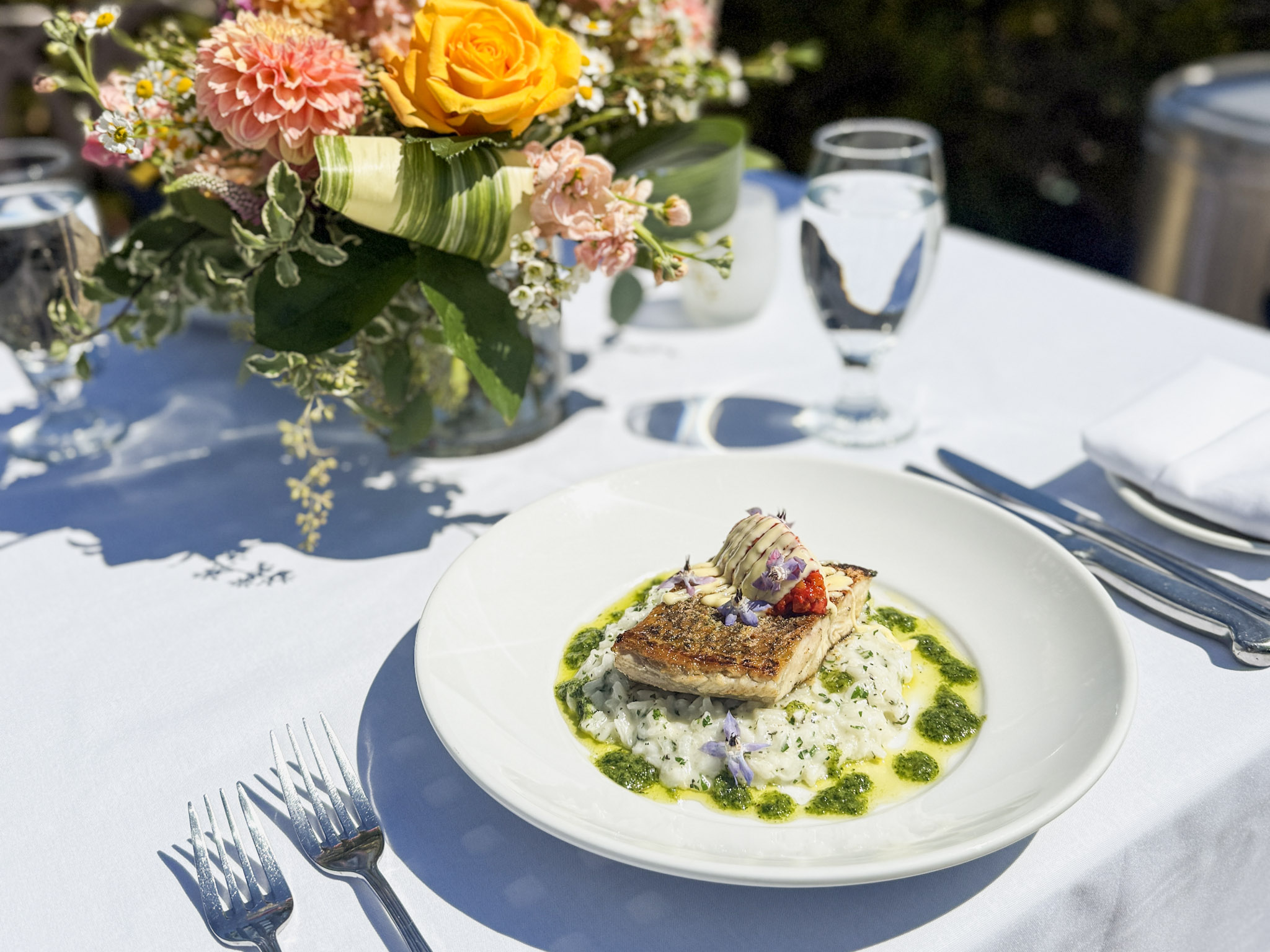 Elegant seafood dish served on a private oceanfront dining table at The Point, Dolphin Bay Resort & Spa in Pismo Beach, adorned with fresh flowers and Pacific views.