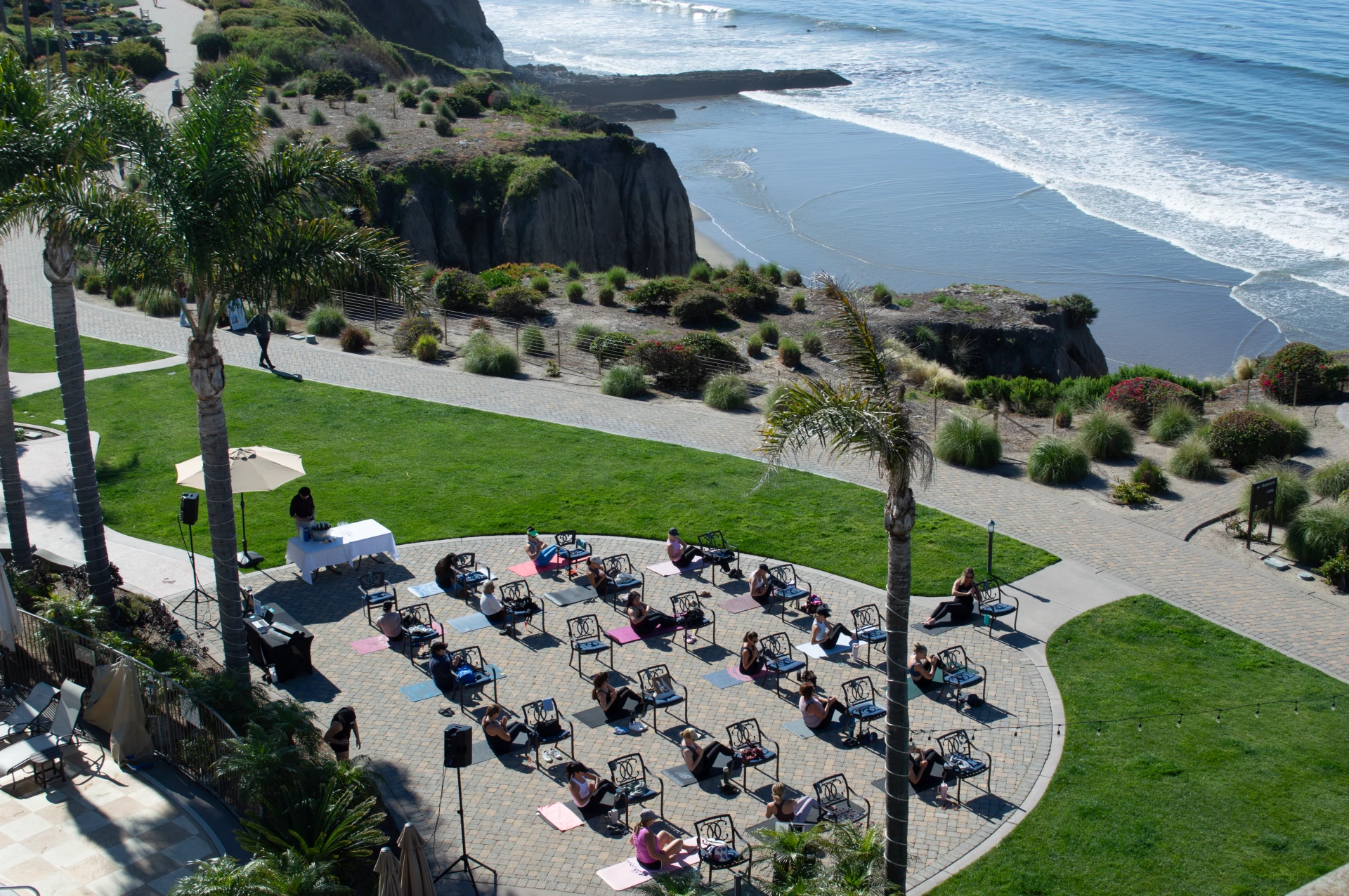 a group of people sitting on chairs on a patio near a body of water