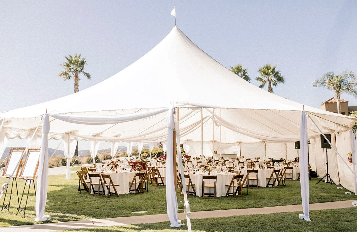 Pacific View Tent at Dolphin Bay Resort & Spa in Pismo Beach — elegant oceanfront event venue with spacious white-lined tables, brown wood chairs, and panoramic coastal views, ideal for large wedding receptions.