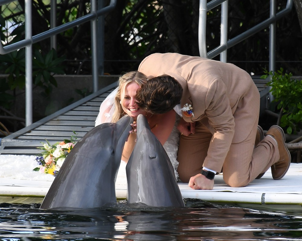 a man and woman kissing dolphins