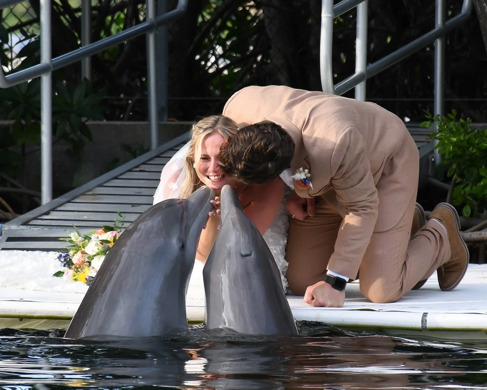 a man and woman kissing dolphins