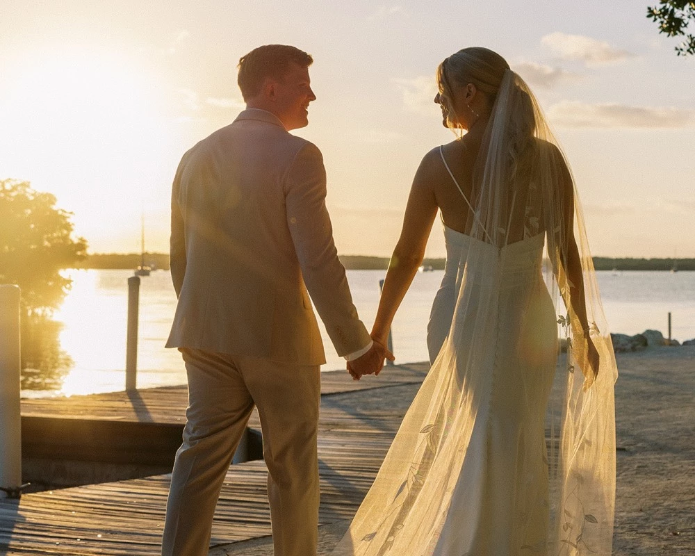 a man and woman holding hands and walking on a dock