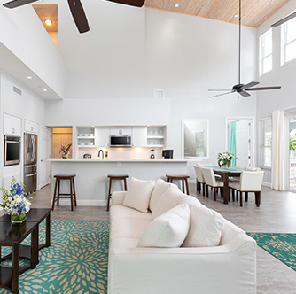 living room with long beige couch and kitchen island behind