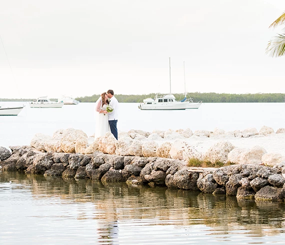 bride and groom kissing at the end of the inlet by rocks