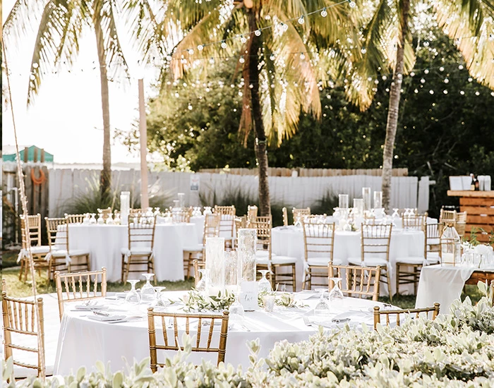 wedding venue with white chairs and round tables outside