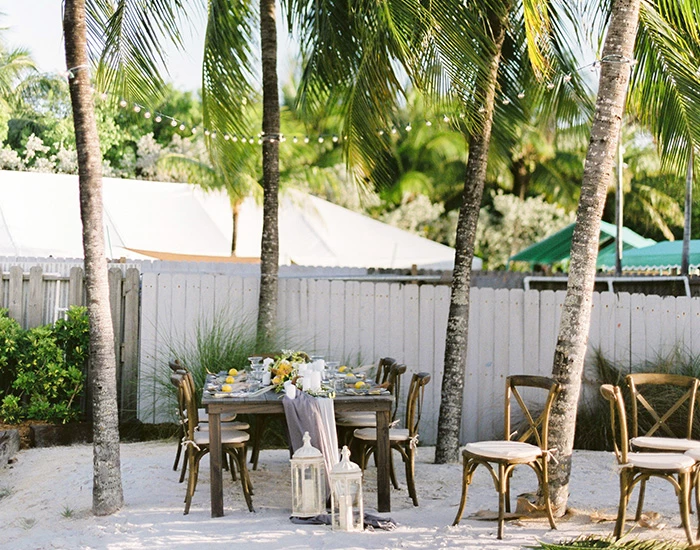 long rectangular wooden table inbetween trees for a venue
