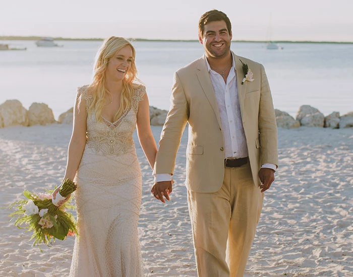 bride and groom walking on the beachy sand at sunset
