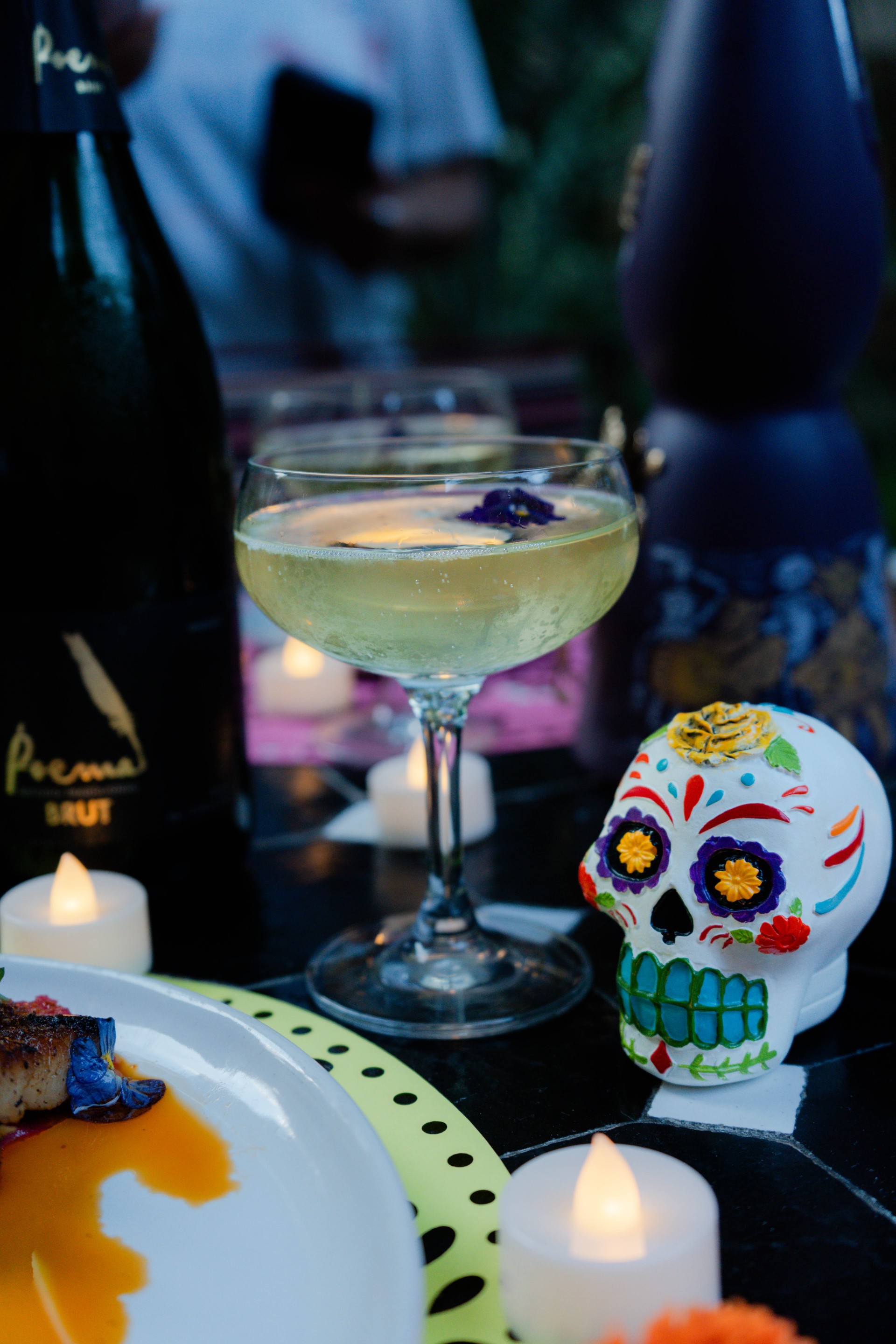 a glass of wine next to a skull