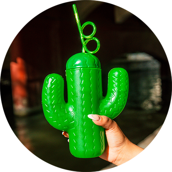 a hand holding a green plastic cup with a straw