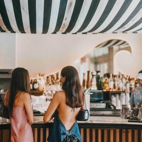 two women standing at a bar