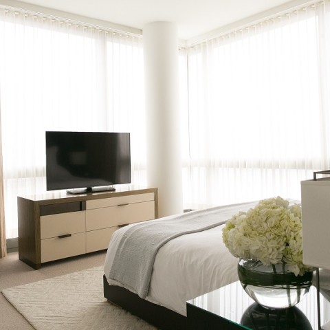 a bedroom with a tv and a vase of flowers